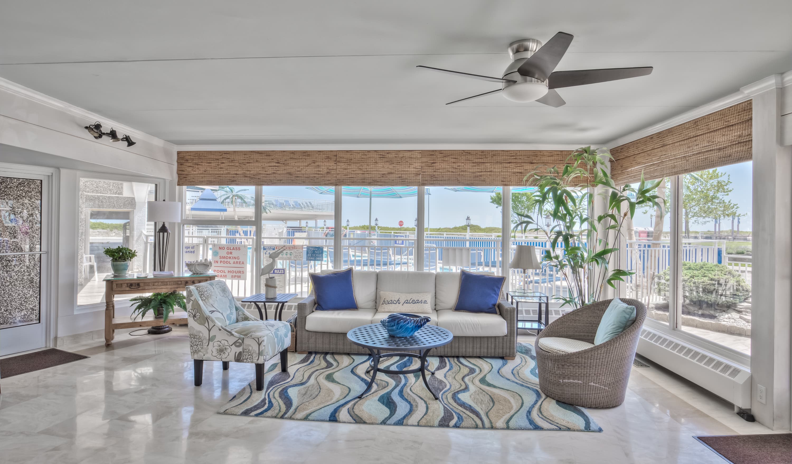 Bright, modern living room with large windows, coastal decor, and a mix of comfortable seating.