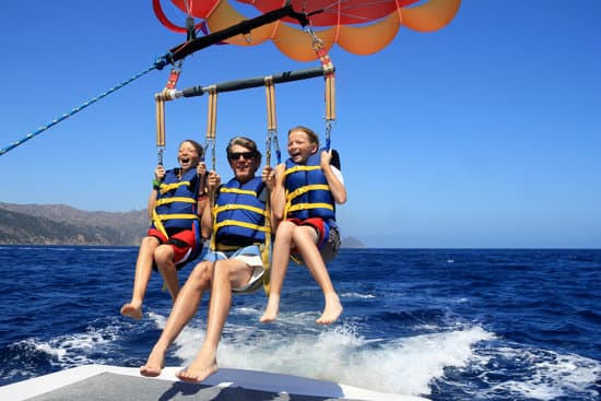 A man and two children enjoy parasailing over the ocean on a sunny day.