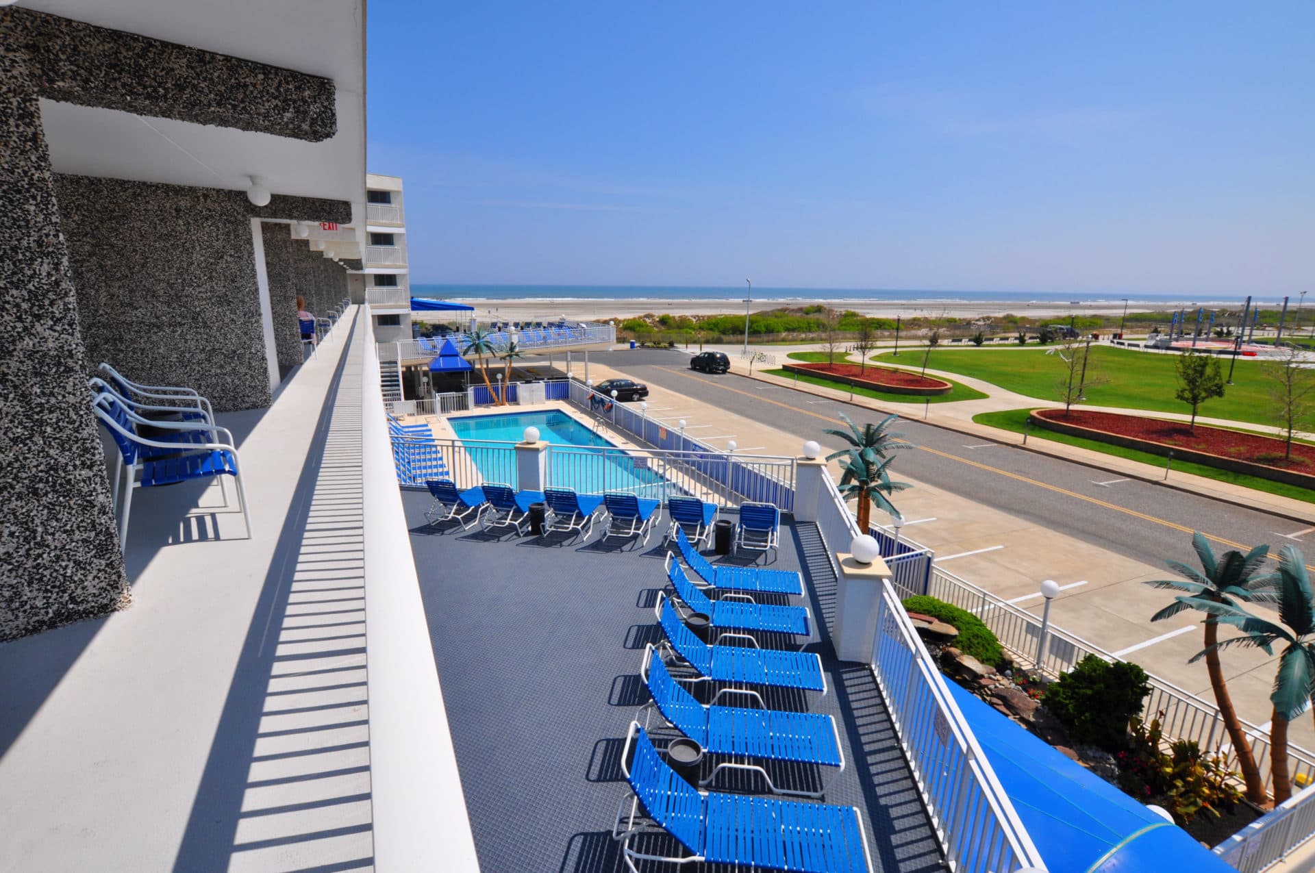 View from a balcony overlooking a pool and the beach.