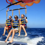 Father and Twin Daughters Parasailing Against a Blue Summer Sky.